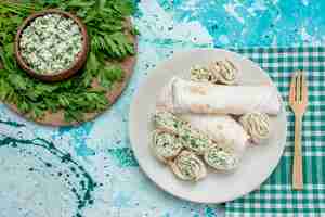 Foto gratuita vista dall'alto di deliziosi involtini di verdure intere e affettate con verdure e insalata sulla scrivania blu, spuntino vegetale