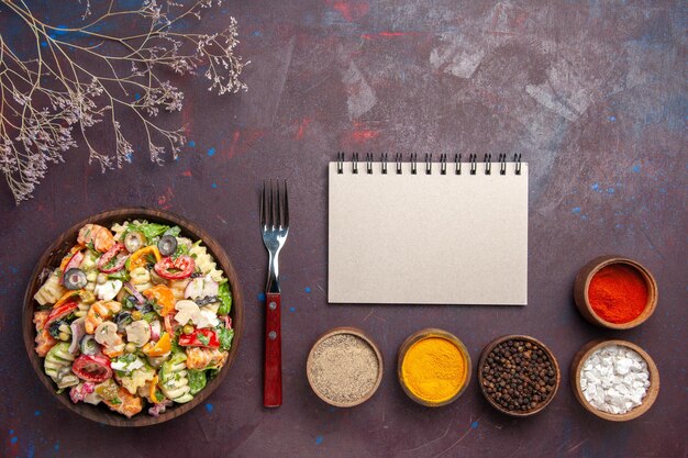 Вид сверху вкусный овощной салат с разными приправами на темном фоне здоровая диета овощной салат обед