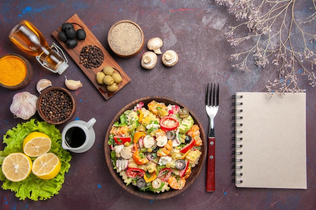 Vista dall'alto deliziosa insalata di verdure con fette di limone fresco sullo spuntino dietetico di insalata di salute sfondo scuro