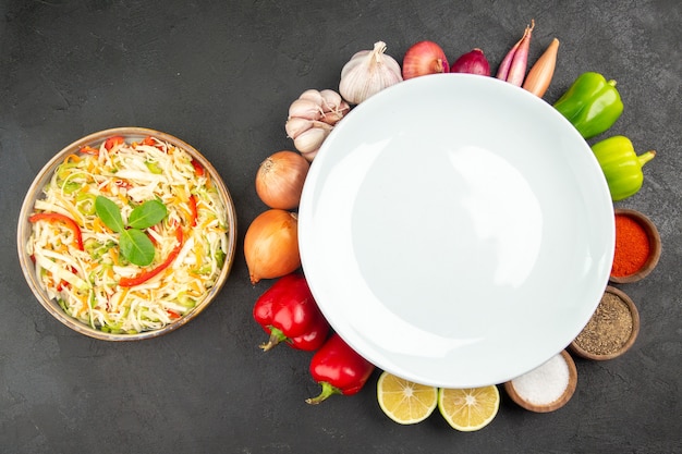 Vista dall'alto deliziosa insalata di verdure con condimenti e verdure fresche sullo sfondo grigio