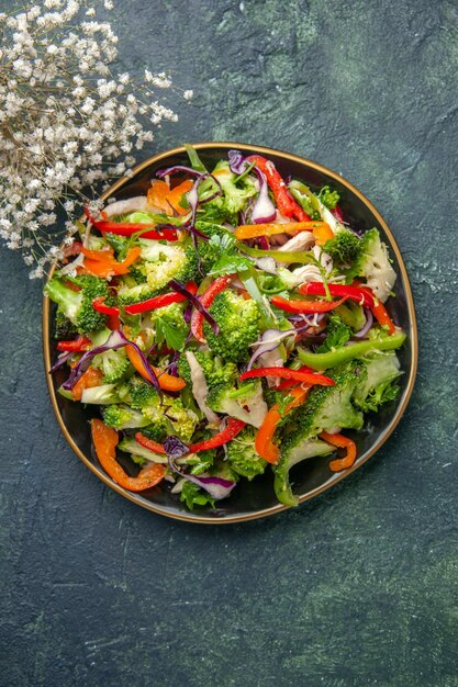 Top view of delicious vegetable salad with various ingredients on black cutting board