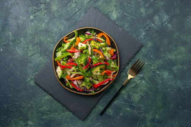 Top view of delicious vegetable salad with various ingredients on black cutting board