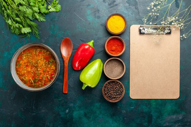 Вид сверху вкусный овощной суп с разными приправами и блокнот на темно-зеленой поверхности еда еда овощной ингредиент суп продукт