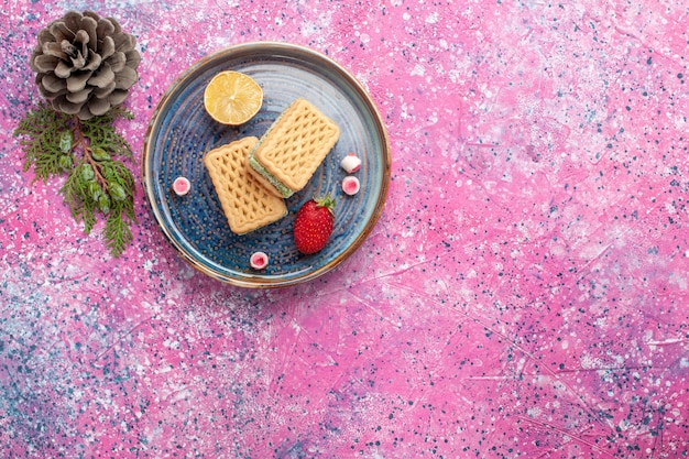 Top view of delicious waffles with strawberry on pink surface