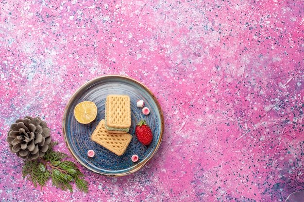 Top view of delicious waffles with strawberry on the pink surface