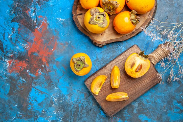 Top view of delicious whole and cut diospyros kaki on brown wooden cutting boards