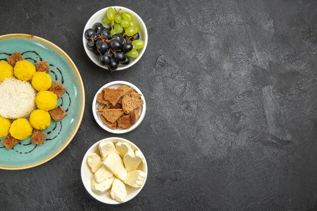 Top view delicious yellow candies with cake grapes and cheese on the dark background sugar fruit candy tea cake sweet