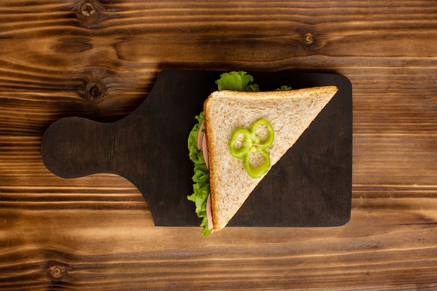 Top view of delicius sandwich with green salad and ham on the wooden surface