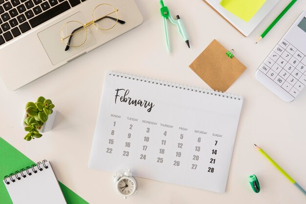 Top view desk calendar and cute indoors plant