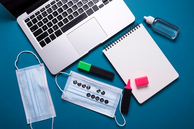 Top view of desk with laptop and medical masks