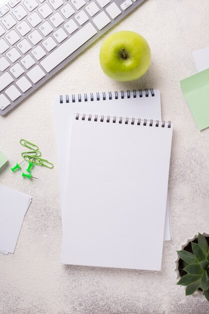 Top view of desk with notebooks and apple