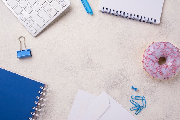 Top view of desk with notebooks and doughnut