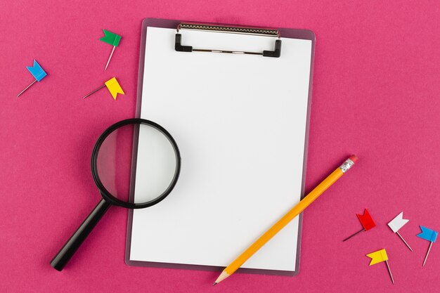 Top view of desk with notepad and magnifying glass