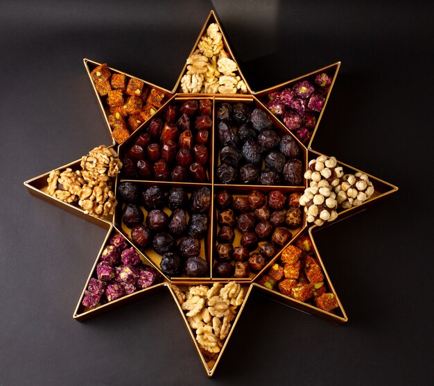 A top view desk with nuts and different dried fruits on the dark surface