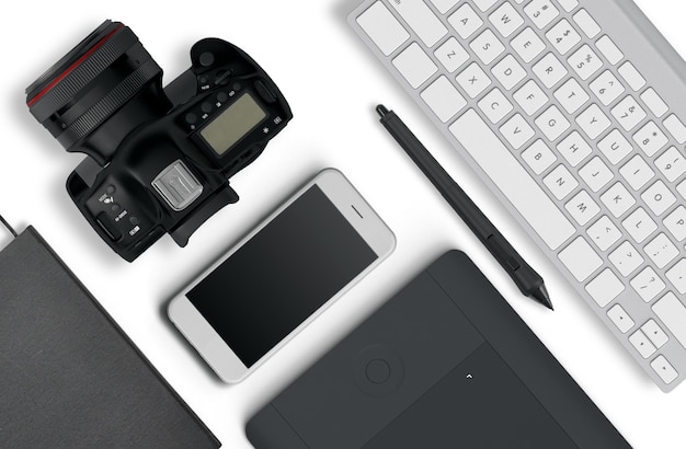 Vista dall'alto di un desktop di un fotografo composto da una fotocamera, una tastiera, uno smartphone su uno sfondo bianco della scrivania. natura morta. disposizione piatta