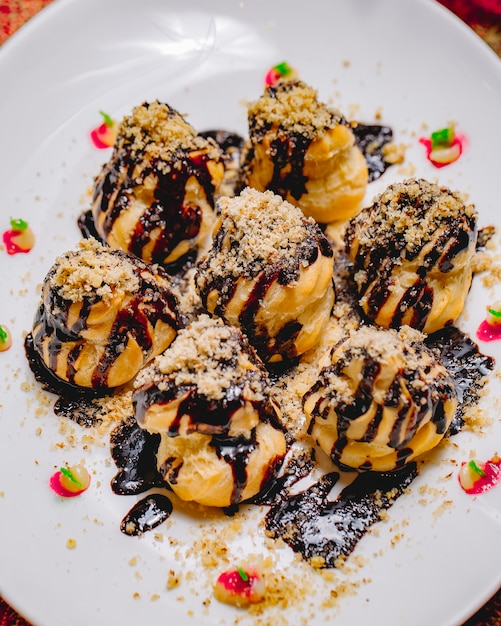 Top view dessert profiteroles with chocolate icing and grated nuts