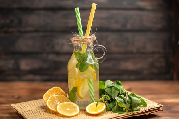 Top view of detox water made of lemon and mint on an old newspaper on brown wooden background