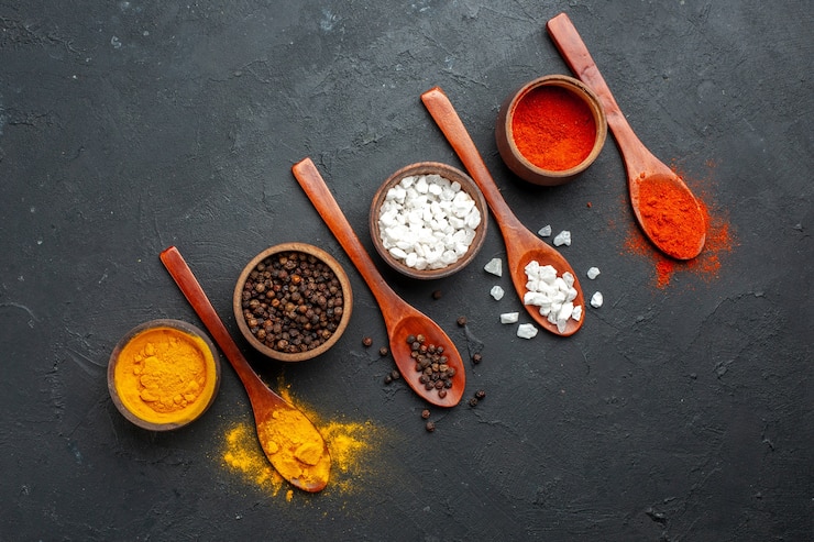 Free Photo top view diagonal row bowls with turmeric black pepper sae salt red pepper powder wooden spoons on black table