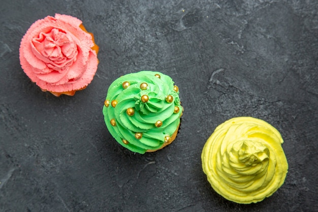 Top view diagonal row mini colorful cupcakes on dark background