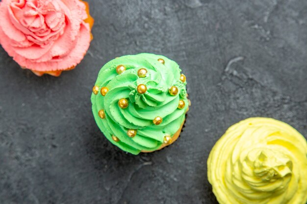 Top view diagonal row mini colorful cupcakes on dark surface