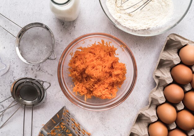 Top view diced carrots in a bowl surrounded by eggs