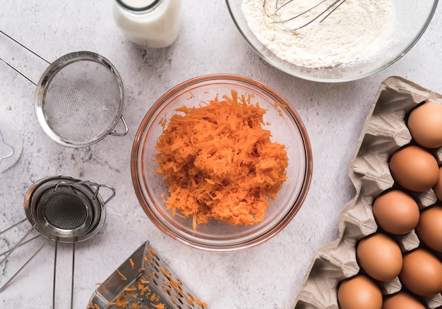 Top view diced carrots in a bowl surrounded by eggs