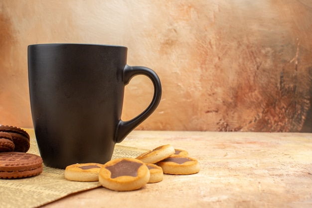 Free photo top view of different biscuits and tea in a black cup on mixed color background