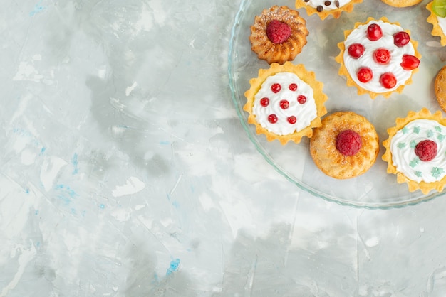 Top view different cakes with cream and fresh fruits on the light surface cookie sugar sweet 