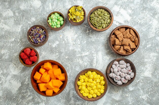 Вид сверху разные конфеты с цветами на белой поверхности цветных конфет, сахара, чая