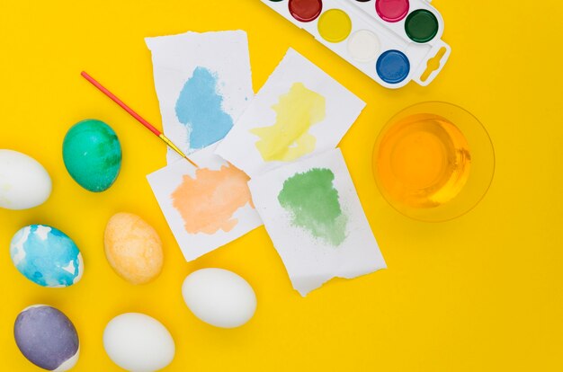 Top view of different colored eggs for easter and stained paper