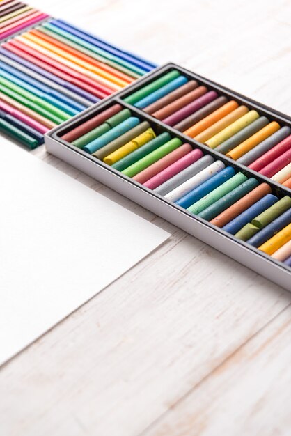 Top view of different colorful pastel paint and markers in boxes on white table