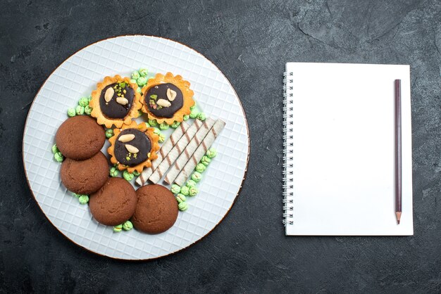 회색 배경에 사탕을 기반으로 한 상위 뷰 다른 쿠키 초콜릿 사탕 봉봉 설탕 달콤한 케이크 쿠키