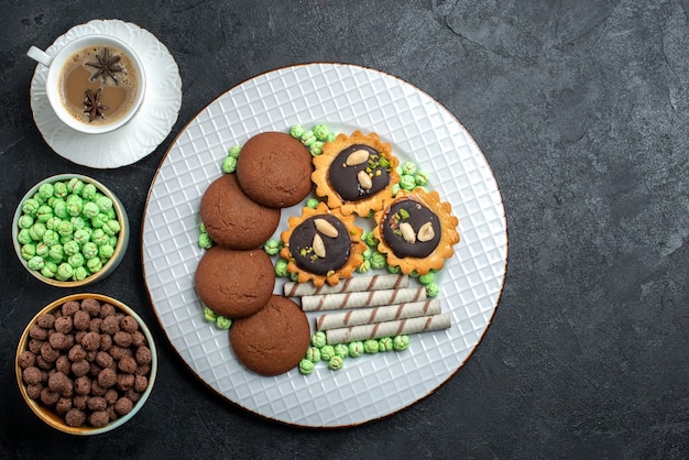 Vista dall'alto diversi biscotti al cioccolato a base di diverse caramelle di zucchero sulla superficie grigio scuro caramelle bonbon zucchero dolce biscotto torta