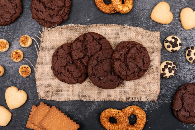 Top view different cookies on sackcloth on dark surface