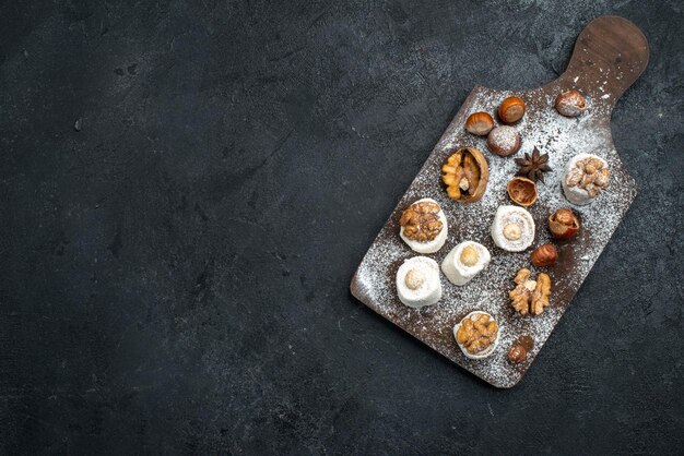 Top view different cookies with cakes and walnuts on the dark grey surface