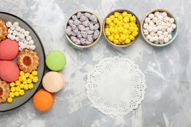 Vista dall'alto diversi biscotti con macarons francesi e caramelle su sfondo bianco zucchero candito dolce cuocere torta biscotto torta di tè