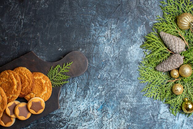 Top view different delicious biscuits and fir branches with pine cone