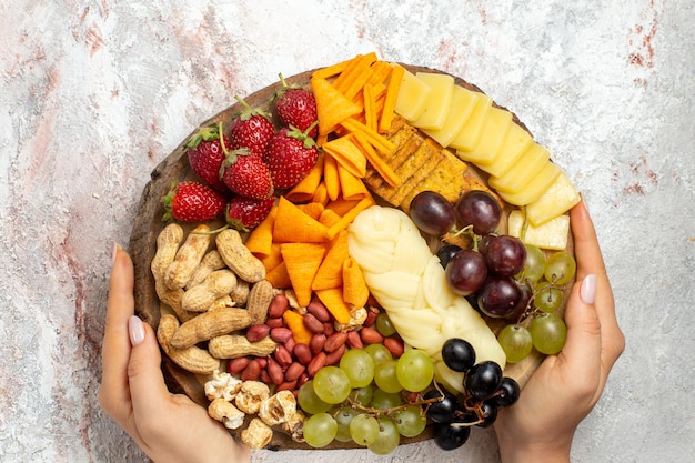 Top view of different delicious snacks fresh grapes cips cheese and nuts on the white surface