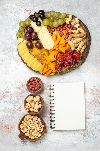 Top view of different delicious snacks fresh grapes cips cheese and nuts on white surface