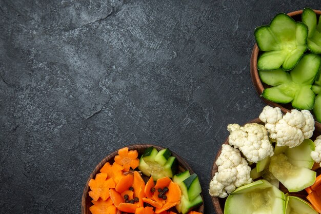 Top view different designed vegetables inside pots on the dark grey space