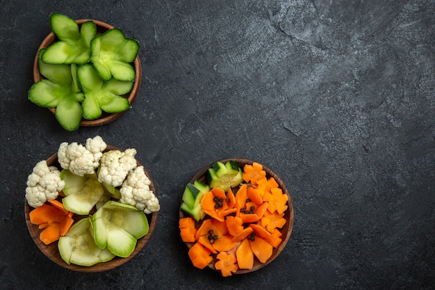 ダークグレーのスペースにある鉢の中のさまざまなデザインの野菜の上面図