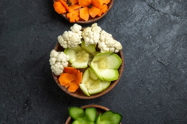 灰色の机の上の鉢の中のさまざまなデザインの野菜の上面図
