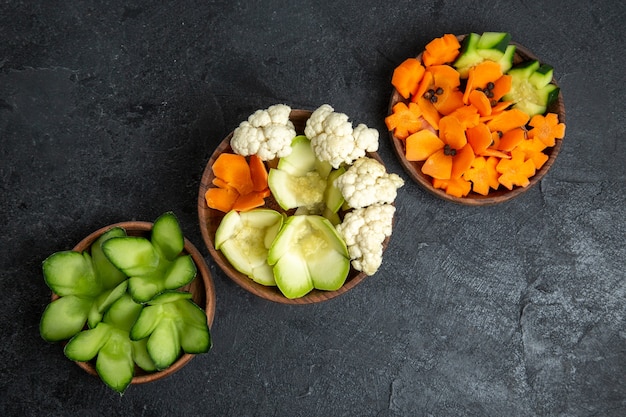 Top view different designed vegetables inside pots on a grey space