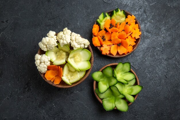 Top view different designed vegetables inside pots on grey space