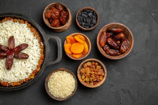 Top view different dried raisins inside pots with plov on dark surface dry fruit sour khurma raisin