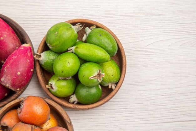 Top view different fresh fruits inside plates on white background exotic tropical ripe diet color healthy life