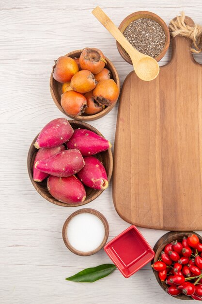 Вид сверху различных свежих фруктов внутри тарелок на белом фоне тропических спелых цветов диеты экзотических здорового образа жизни