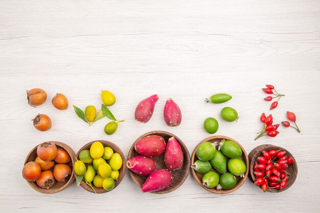 Вид сверху различных свежих фруктов внутри тарелок на белом фоне тропической спелой диеты цвет здорового образа жизни