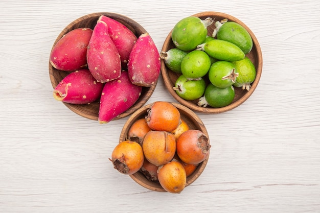 Top view different fresh fruits inside plates on white desk fruit tropical ripe diet exotic color healthy life