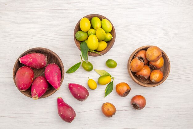 Top view different fresh fruits inside plates on white desk fruit tropical ripe diet exotic color